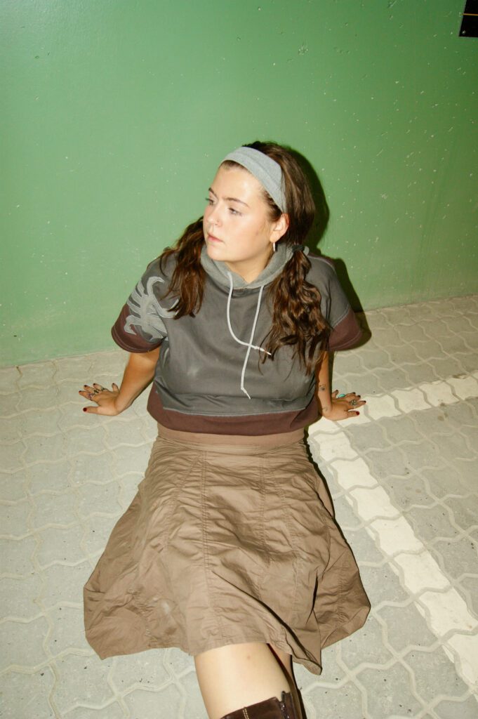 Model i brun/grå PATAKO STUDIOS hoodie, upcycled med korte ærmer og organisk mønster.